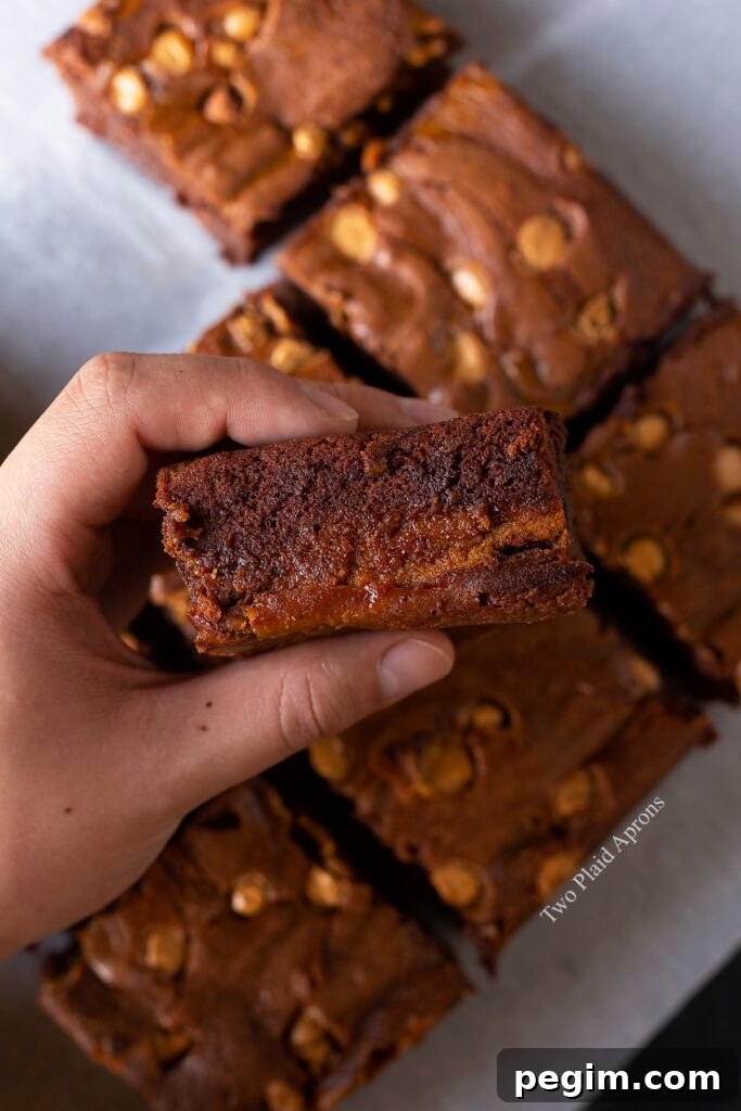 Holding a piece of pumpkin butterscotch brownies sideways to show interior.