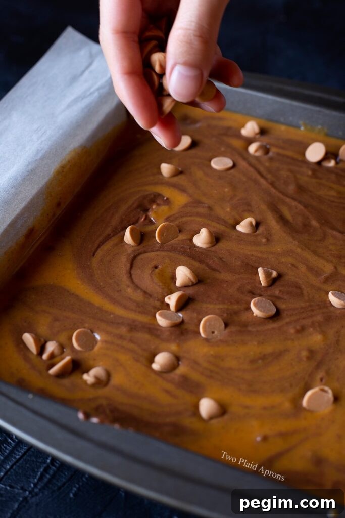 Sprinkling butterscotch chips onto the brownie batter.