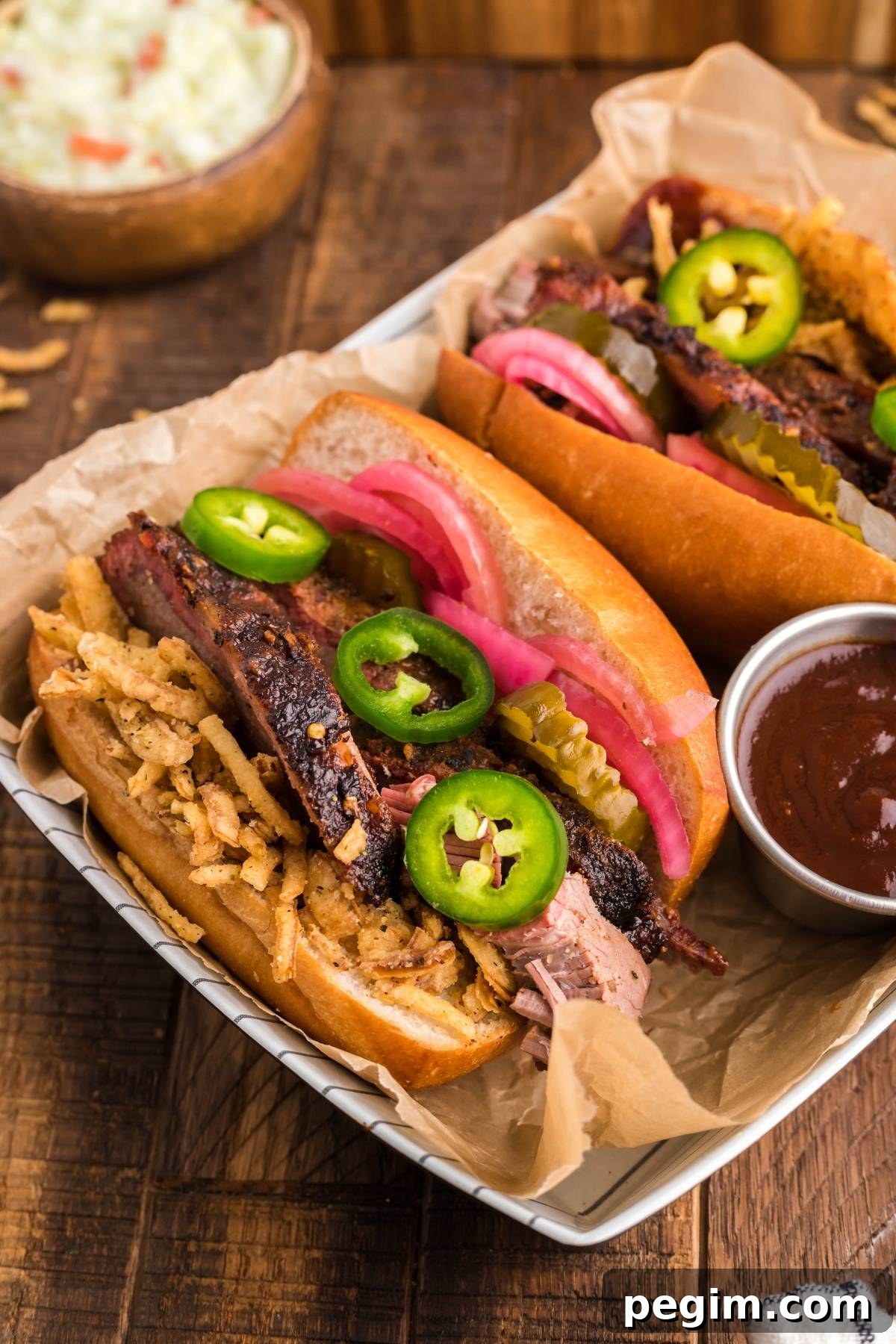 Brisket sandwich using leftover brisket topped with fried onions, pickles and jalapeños with pickled red onions and barbecue sauce.