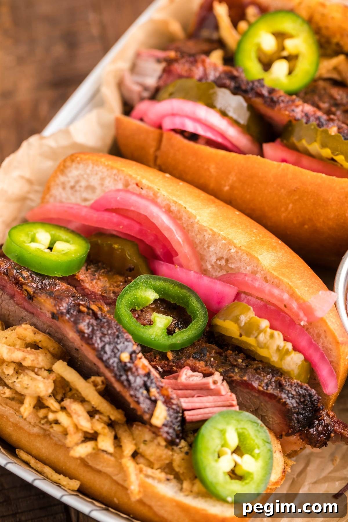 Smoked brisket sandwich topped with pickles, jalapeños, pickled onions and crispy fried onions on a bun.