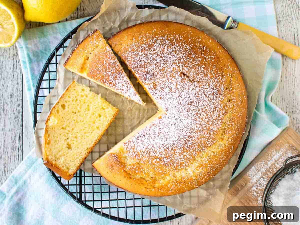 Yellow cake dusted with powdered sugar with a few slices cut viewed from above.