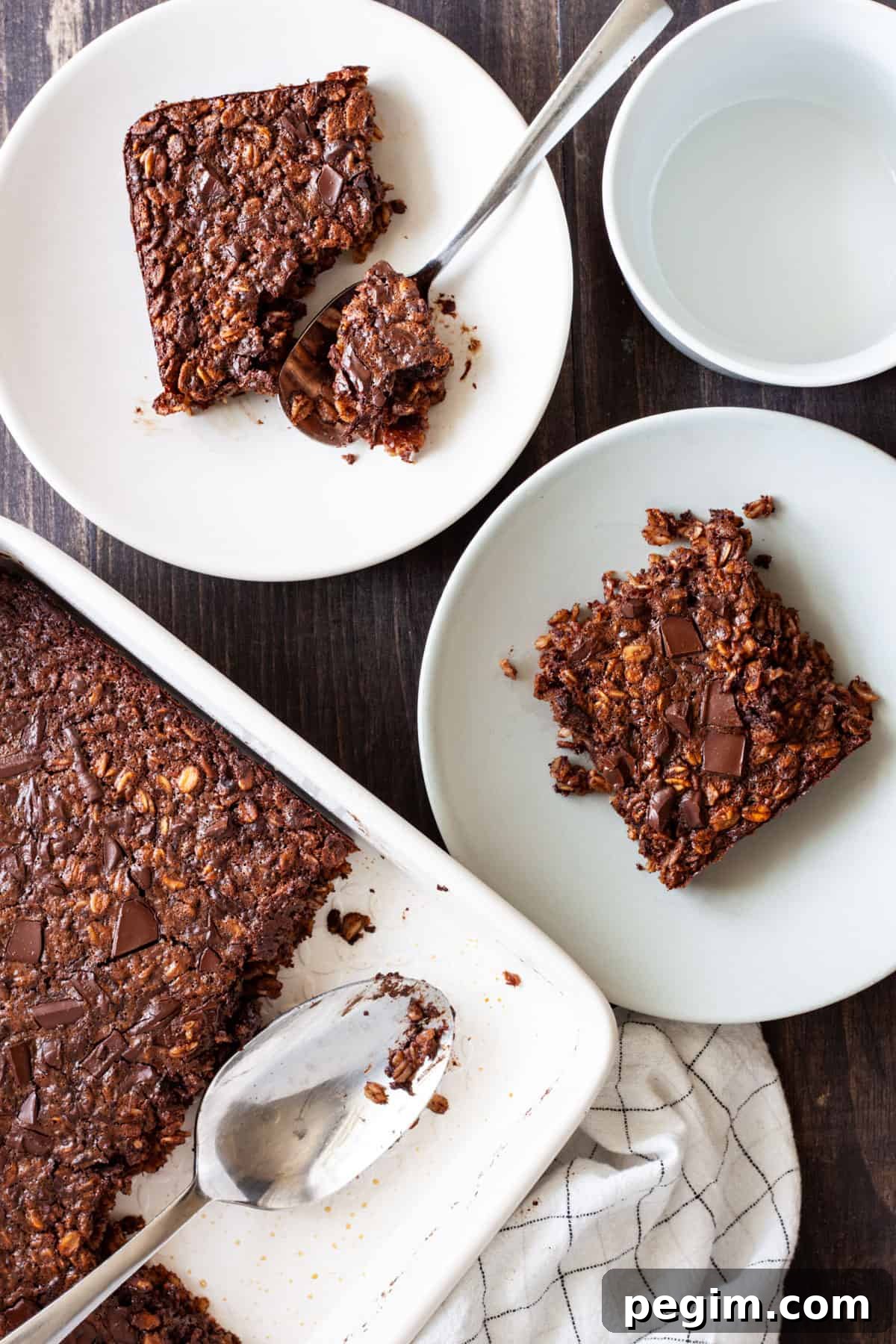 A baking dish of chocolate baked oatmeal with two portions on small plates.