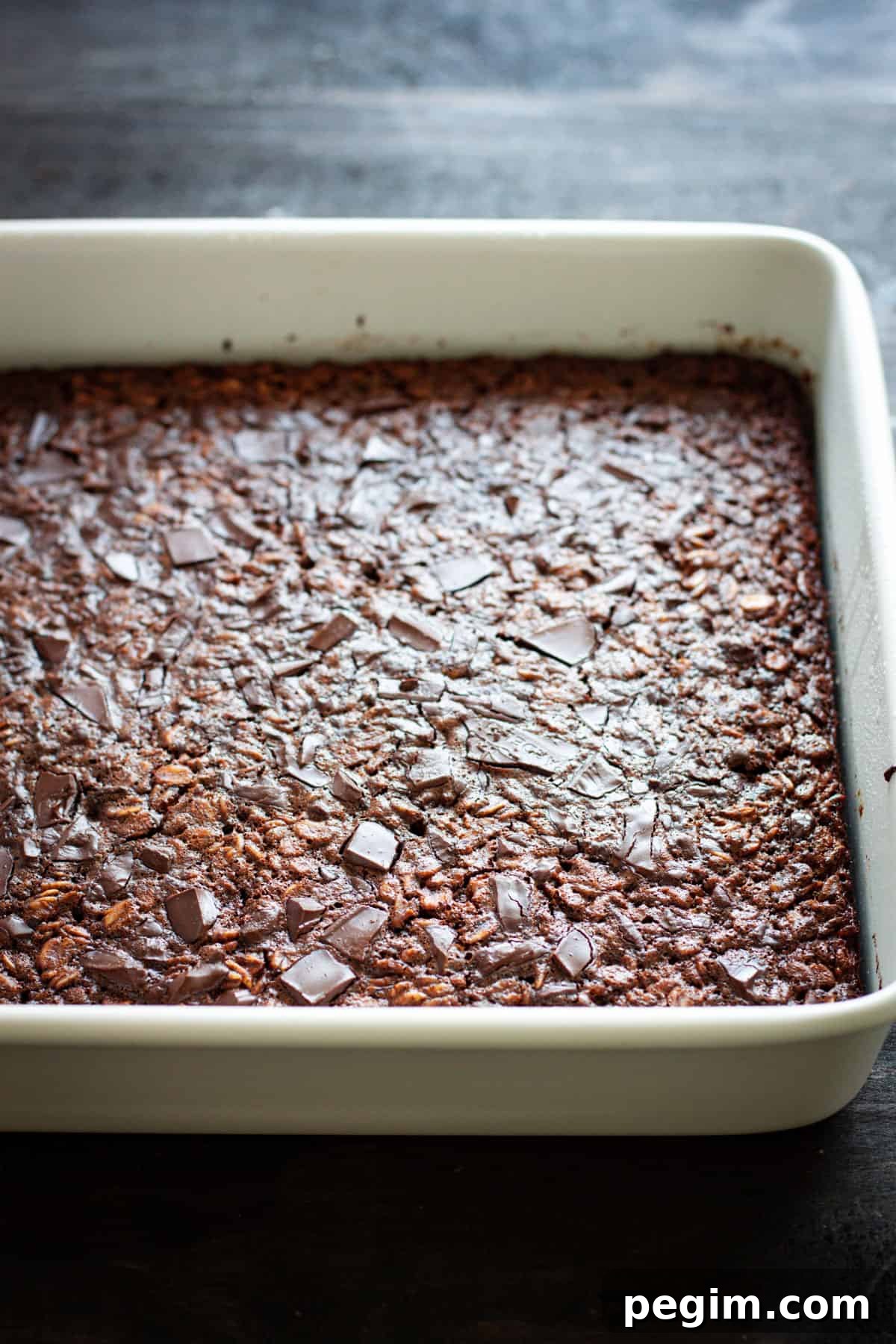 Chocolate baked oatmeal in a square baking dish on a dark table.