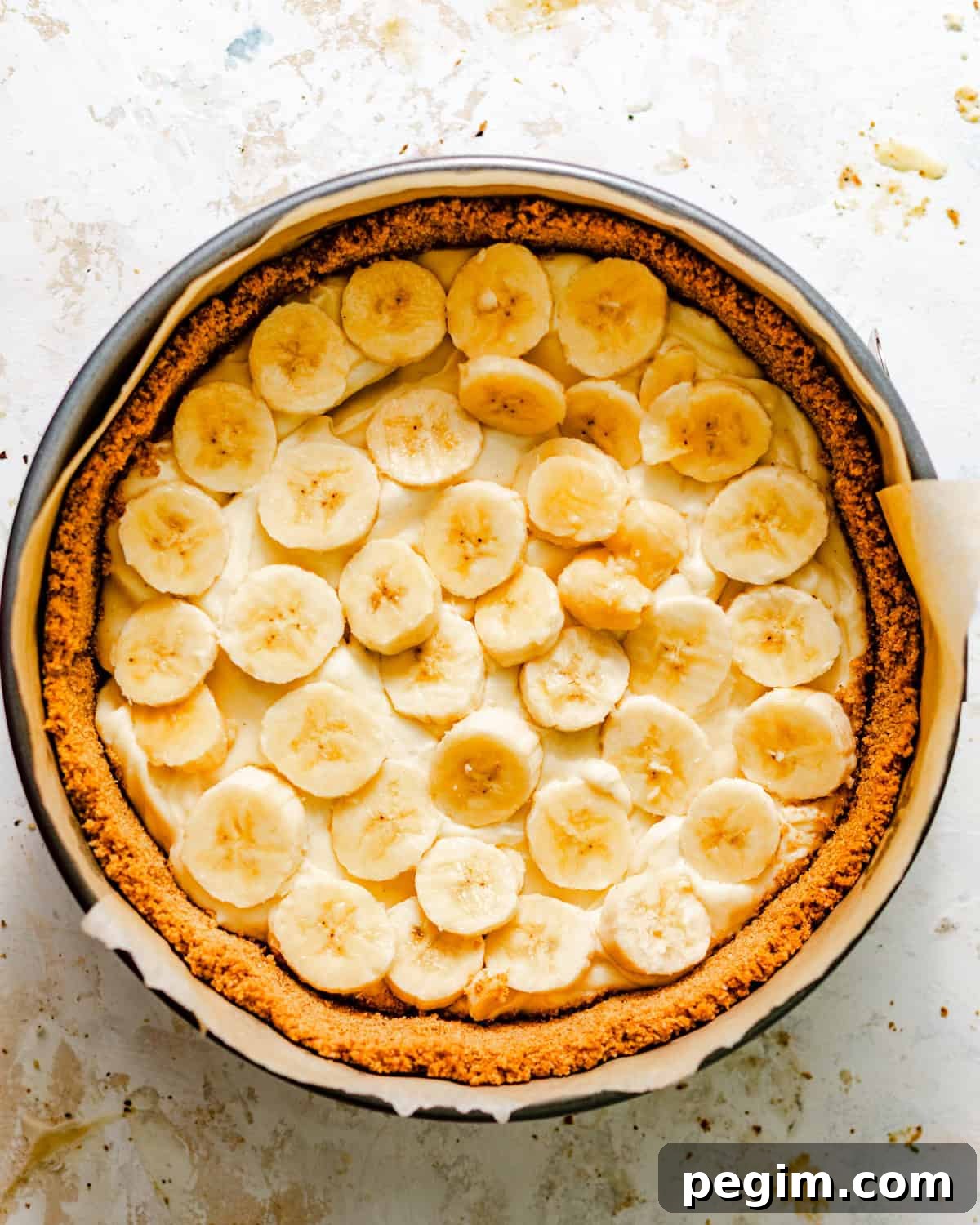 half of the cream filling in a springform pan with sliced bananas on top.