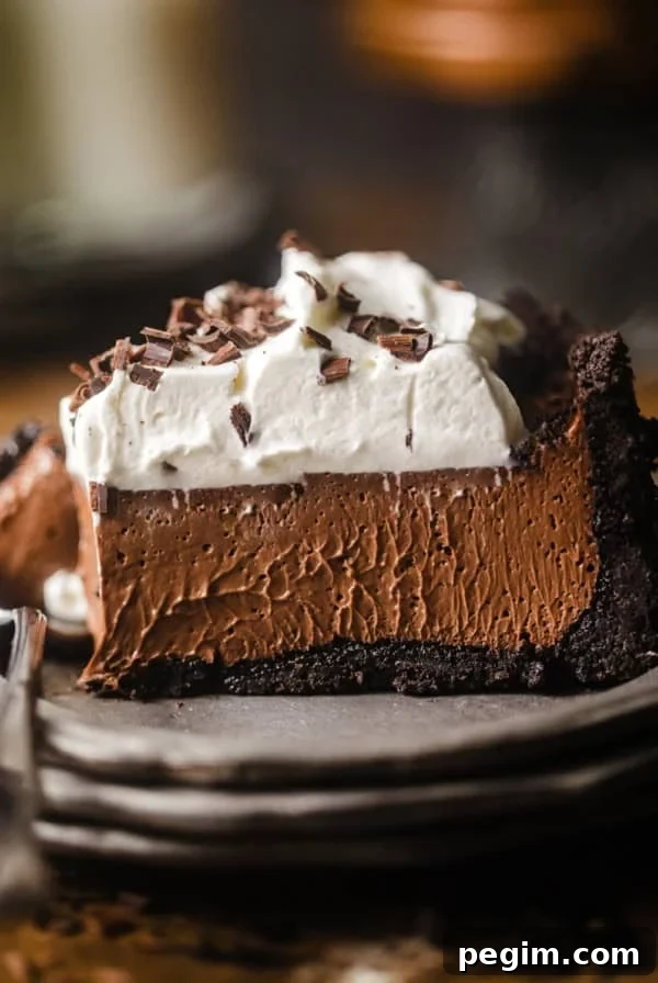 a slice of chocolate mousse pie on a plate topped with whipped cream and chocolate curls.