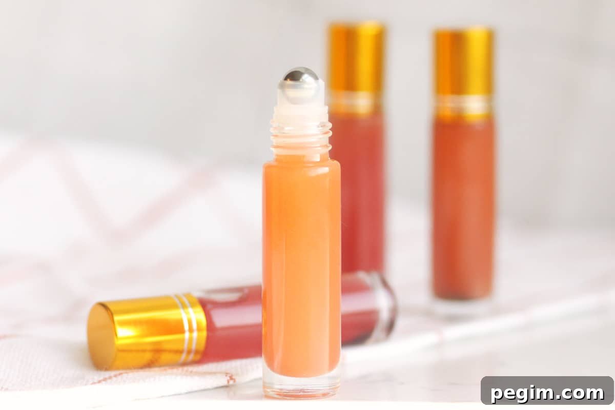 a pink lip gloss in a roller ball bottle with several bottles in the background