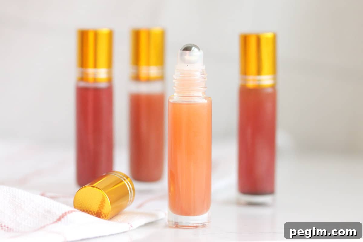 a pink lip gloss in a roller ball bottle with several bottles in the background