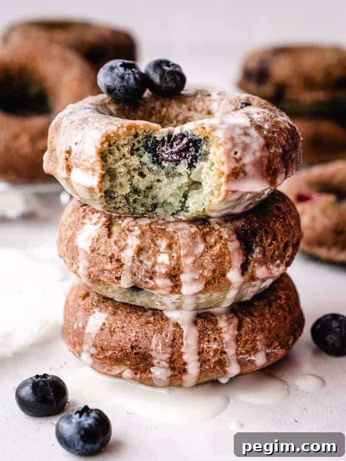 stack of 3 blueberry cake donuts, top donut with bite taken out