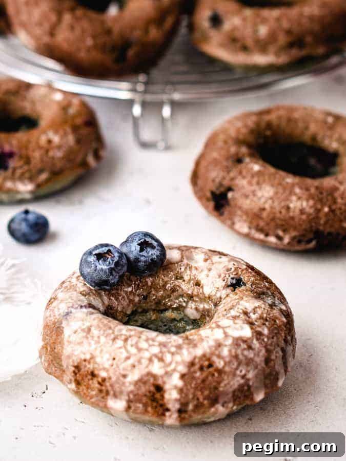 Close up for blueberry cake donut with glaze on it and 2 blueberries sitting on top