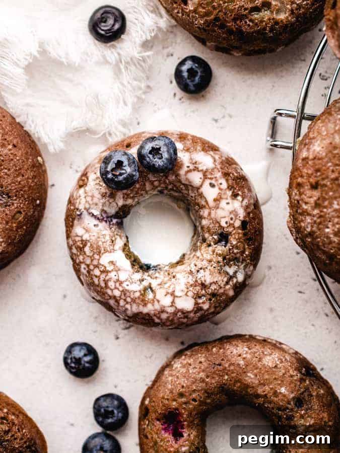 Overhead of blueberry cake donut covered in glaze with 2 blueberries on it
