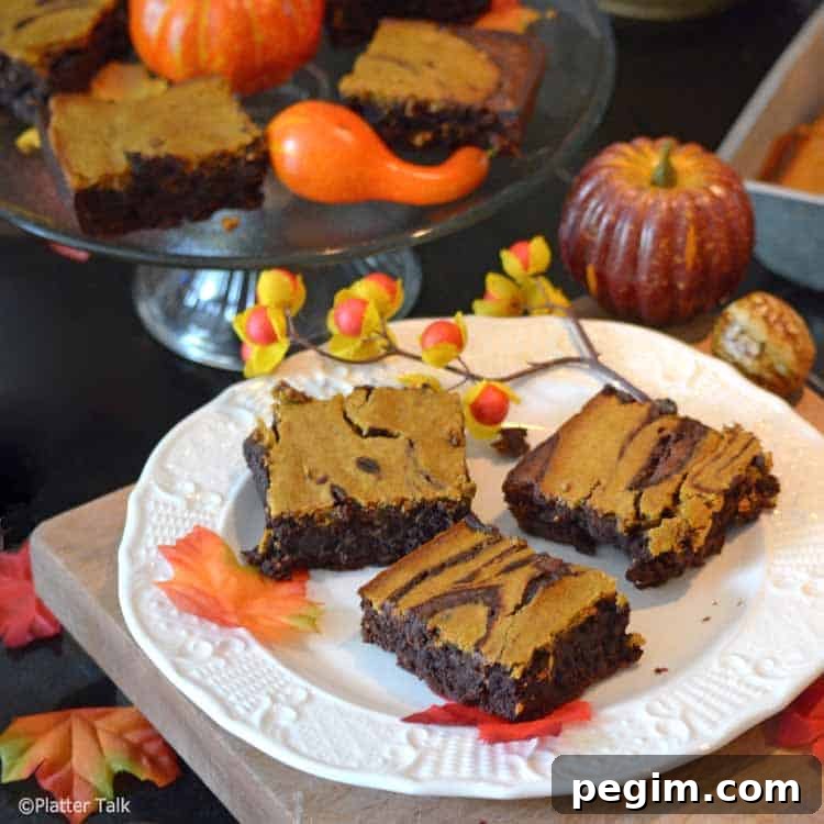 Pumpkin Cheesecake Brownies Recipe — Gooey Fall Dessert 3 pumpkin cheesecake brownies on a platter.