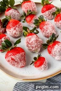 champagne soaked strawberries dipped in sugar aligned on white plate.