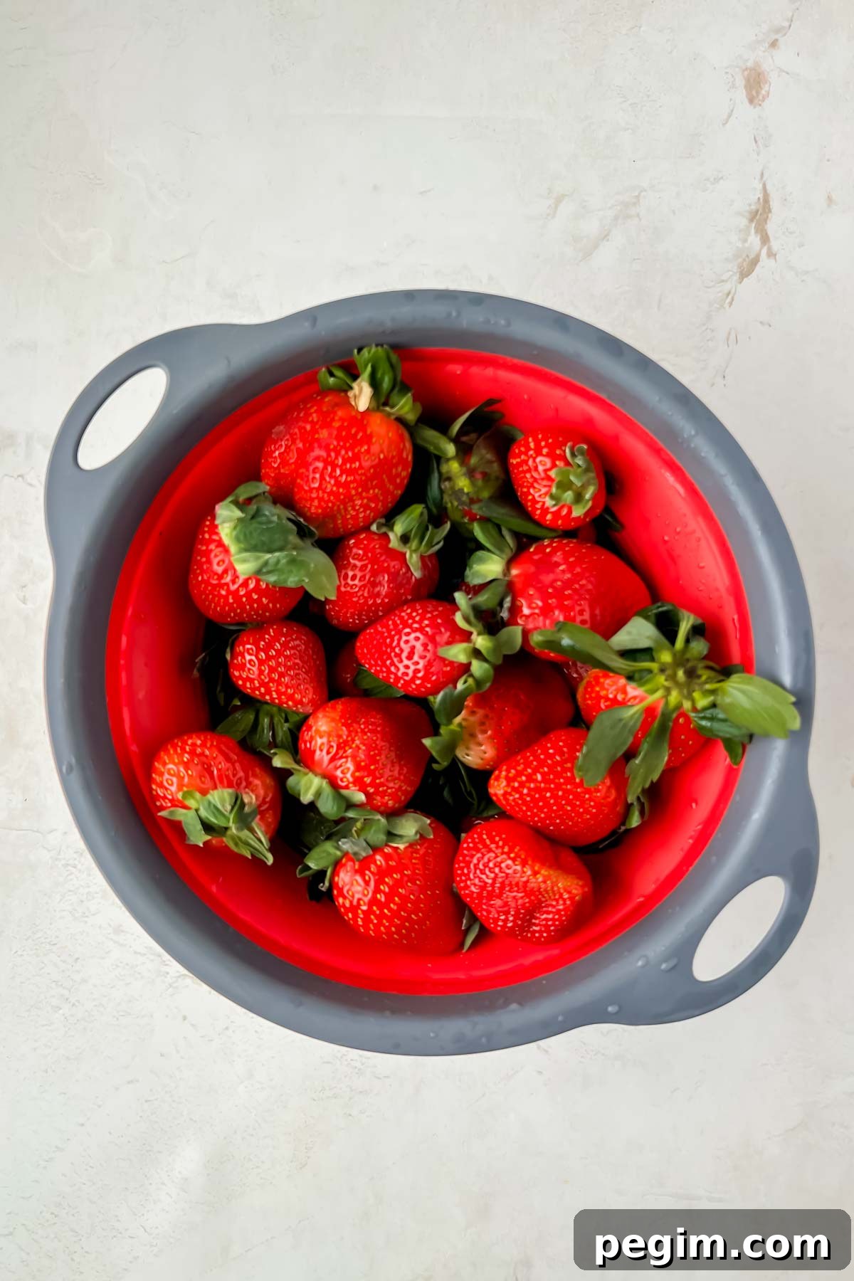 fresh strawberries in red strainer.