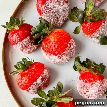 champagne soaked strawberries dipped in sugar aligned on white plate.