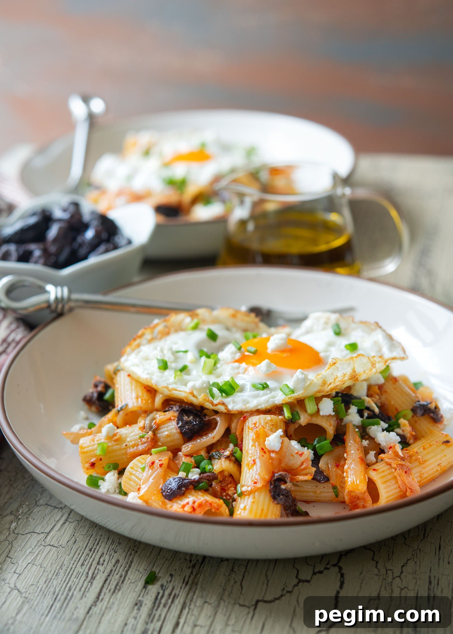 Kimchi olive pasta featuring feta cheese and fried egg as a Greek-Korean fusion dish.