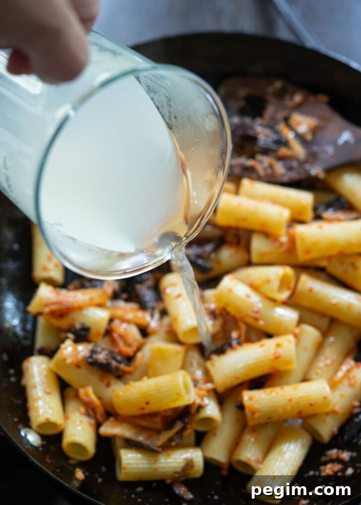 Pasta water is added to kimchi olive pasta.
