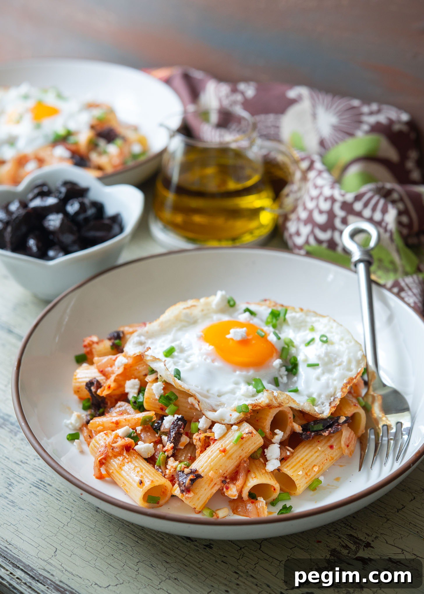 Fried egg topped over kimchi olive pasta, the Greek-Korean fusion recipe.