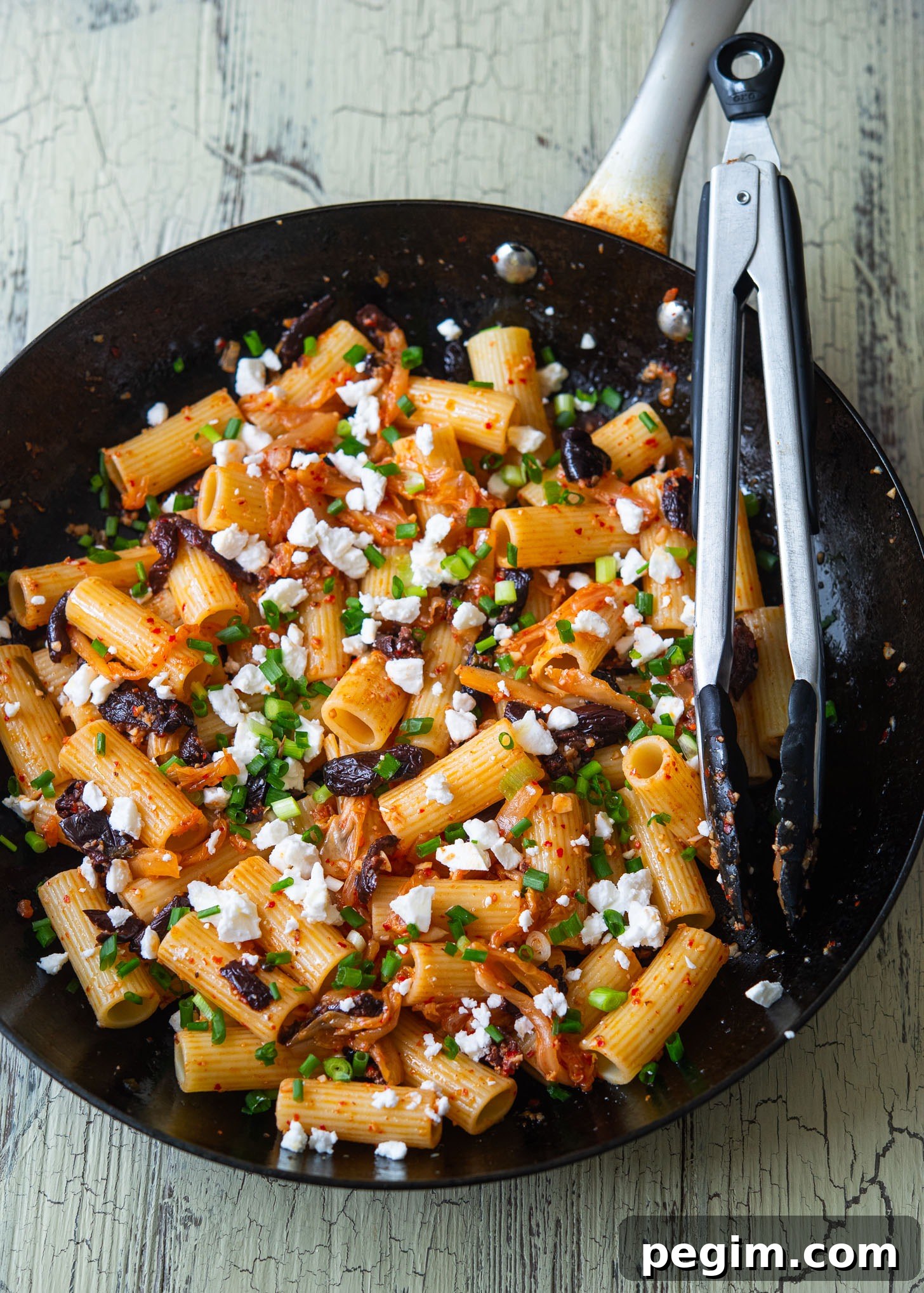 A skillet filled with kimchi olive pasta, Greek-Korean fusion style.