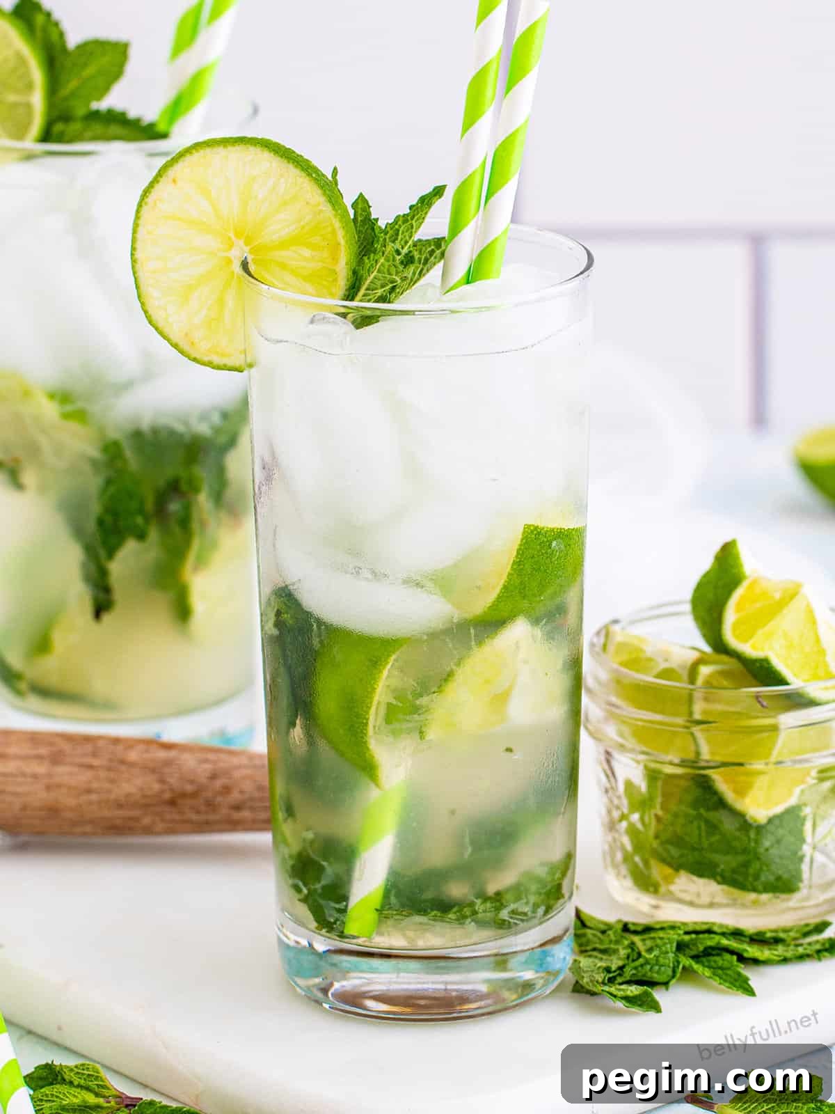 A classic mojito with a small glass of lime wedges to the side