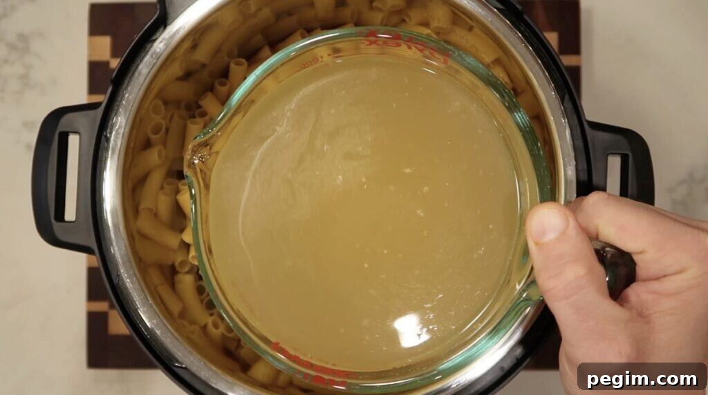 Broth being poured into Instant Pot with pasta