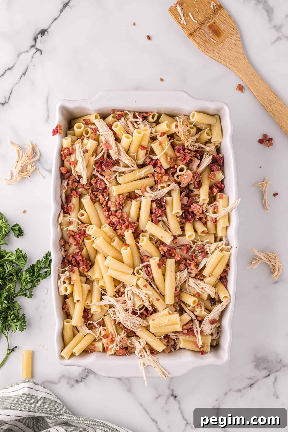 Casserole dish with ziti, crumbled bacon, shredded cooked chicken