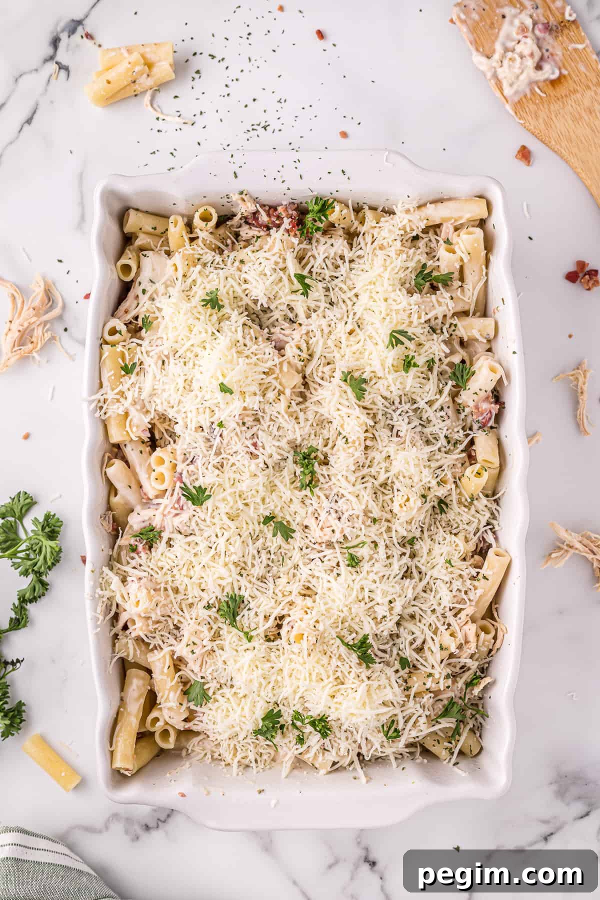 Unbaked chicken Alfredo casserole, topped with shredded cheese and parsley
