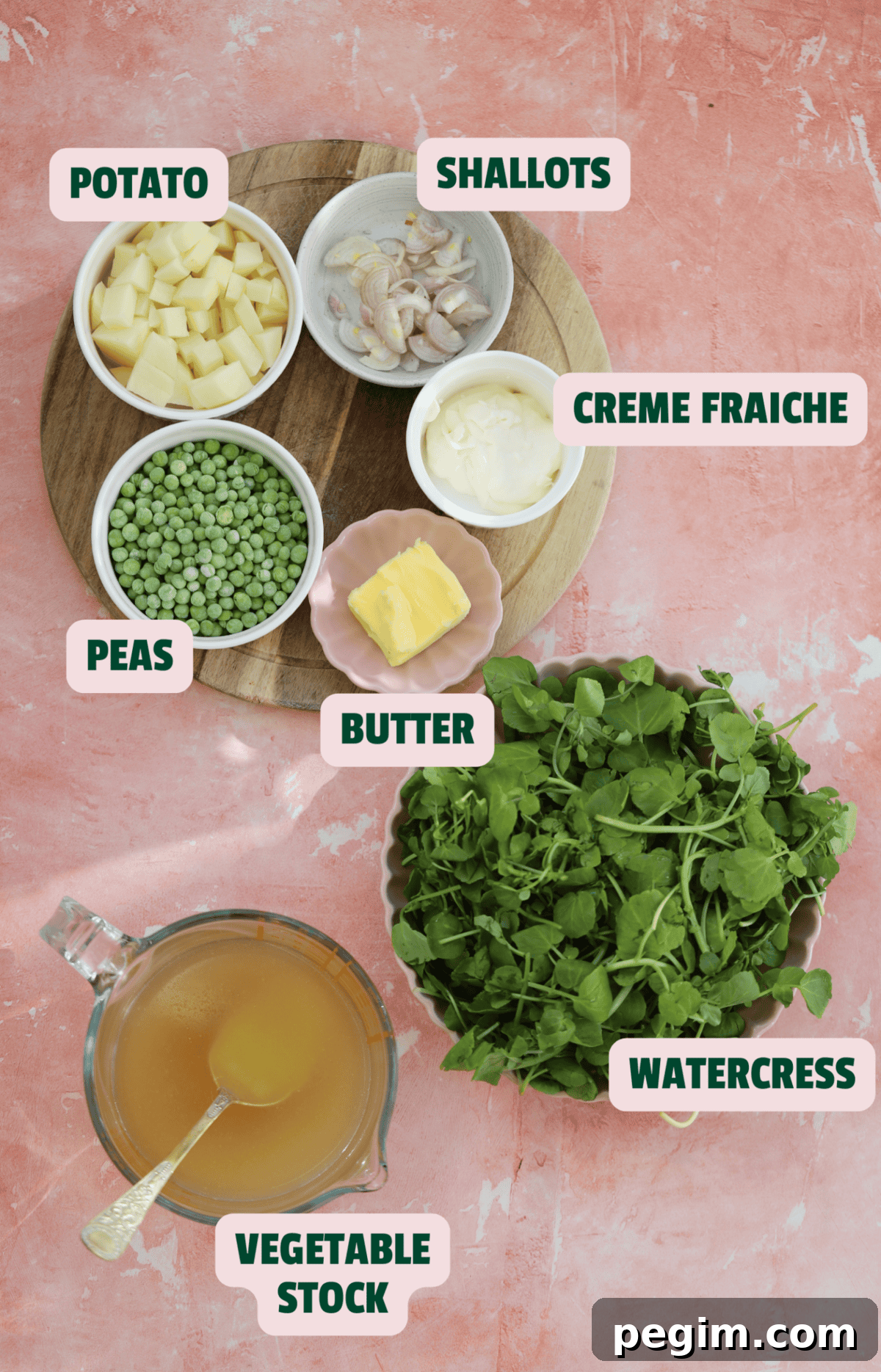 Ingredients for watercress soup on a pink backdrop with text labels.