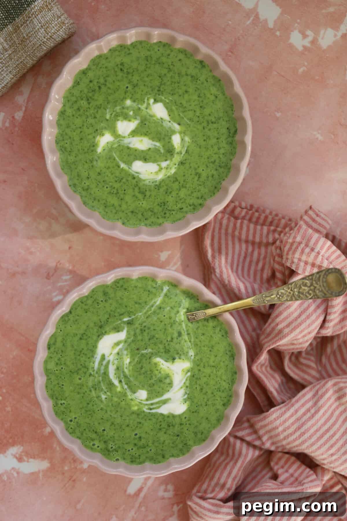 Two bowls of gluten free watercress soup on a pink backdrop.