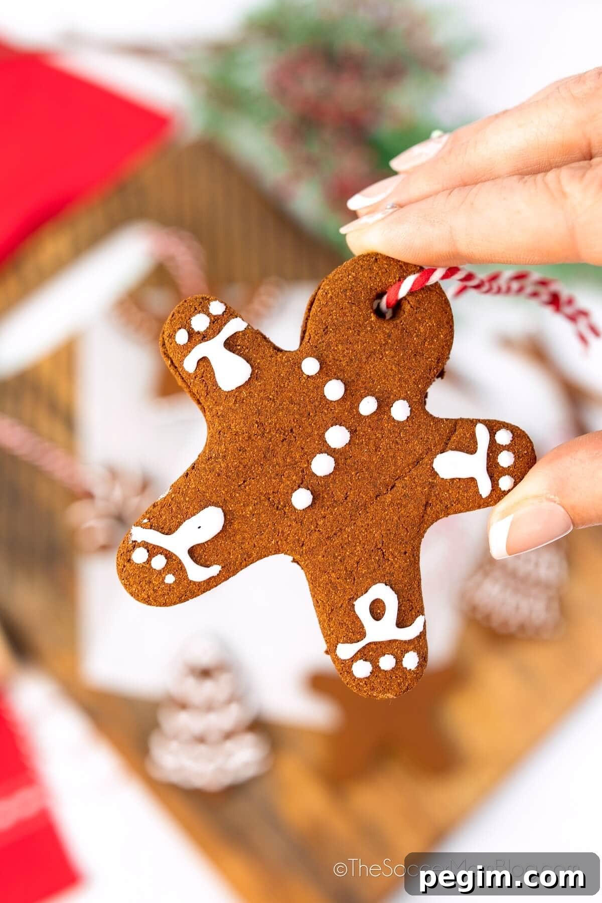 hand holding a homemade cinnamon ornament shaped like a gingerbread man.
