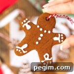 hand holding a homemade cinnamon ornament shaped like a gingerbread man.