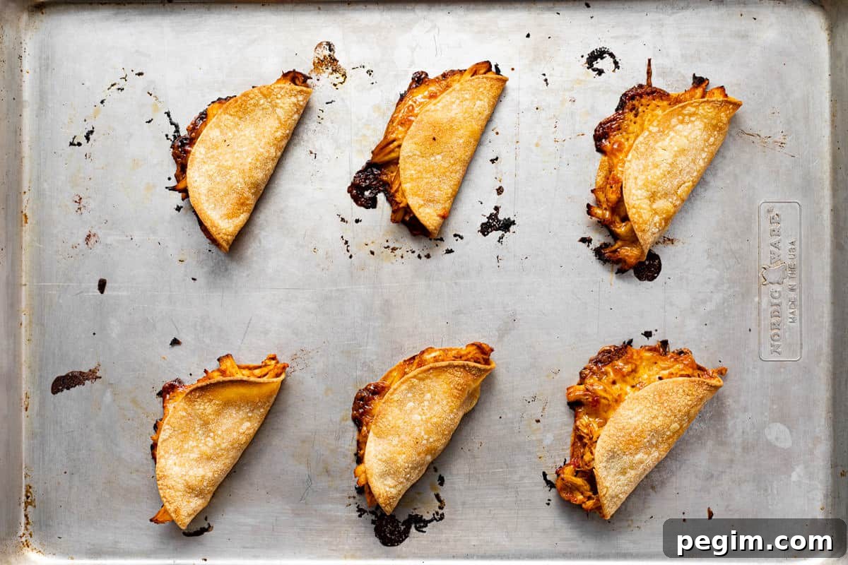 Freshly baked mini chicken tacos on a metal baking sheet.