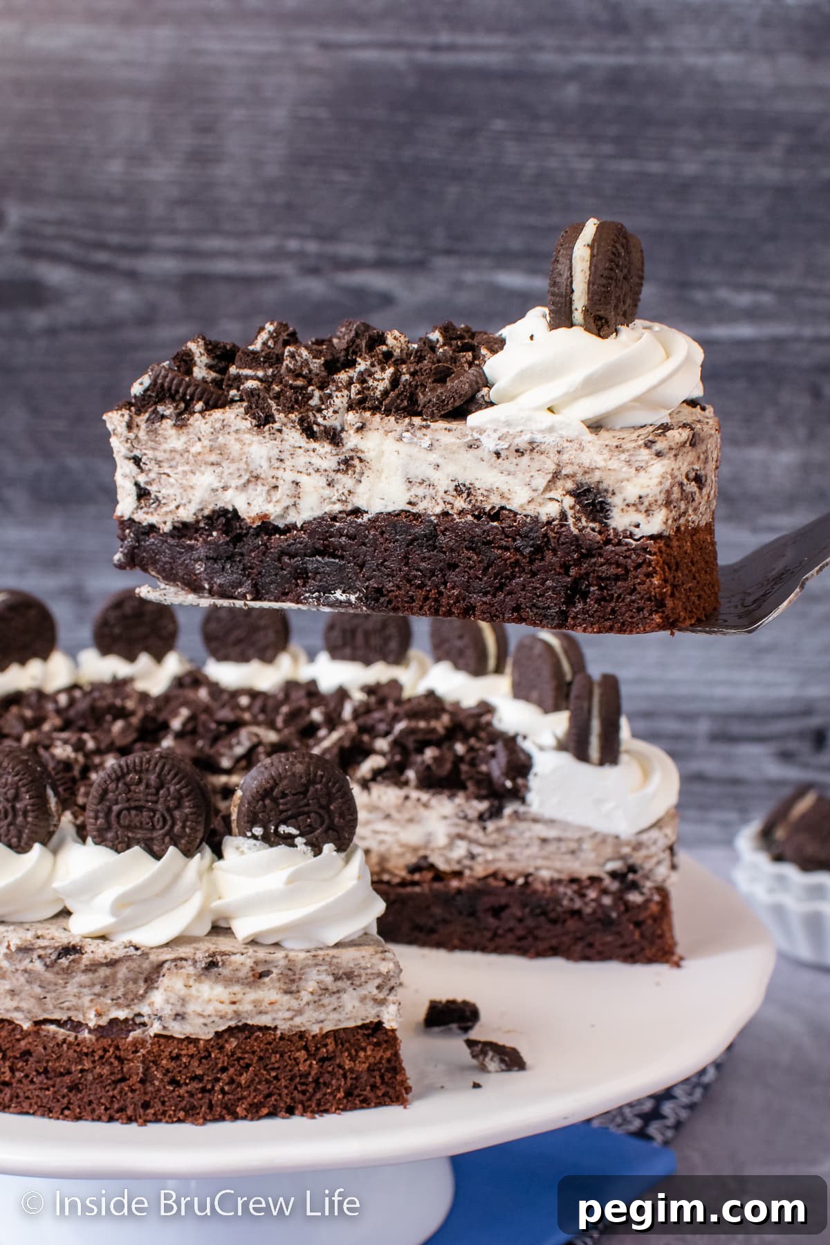 A slice of Oreo brownie cake being lifted out of a full cake.