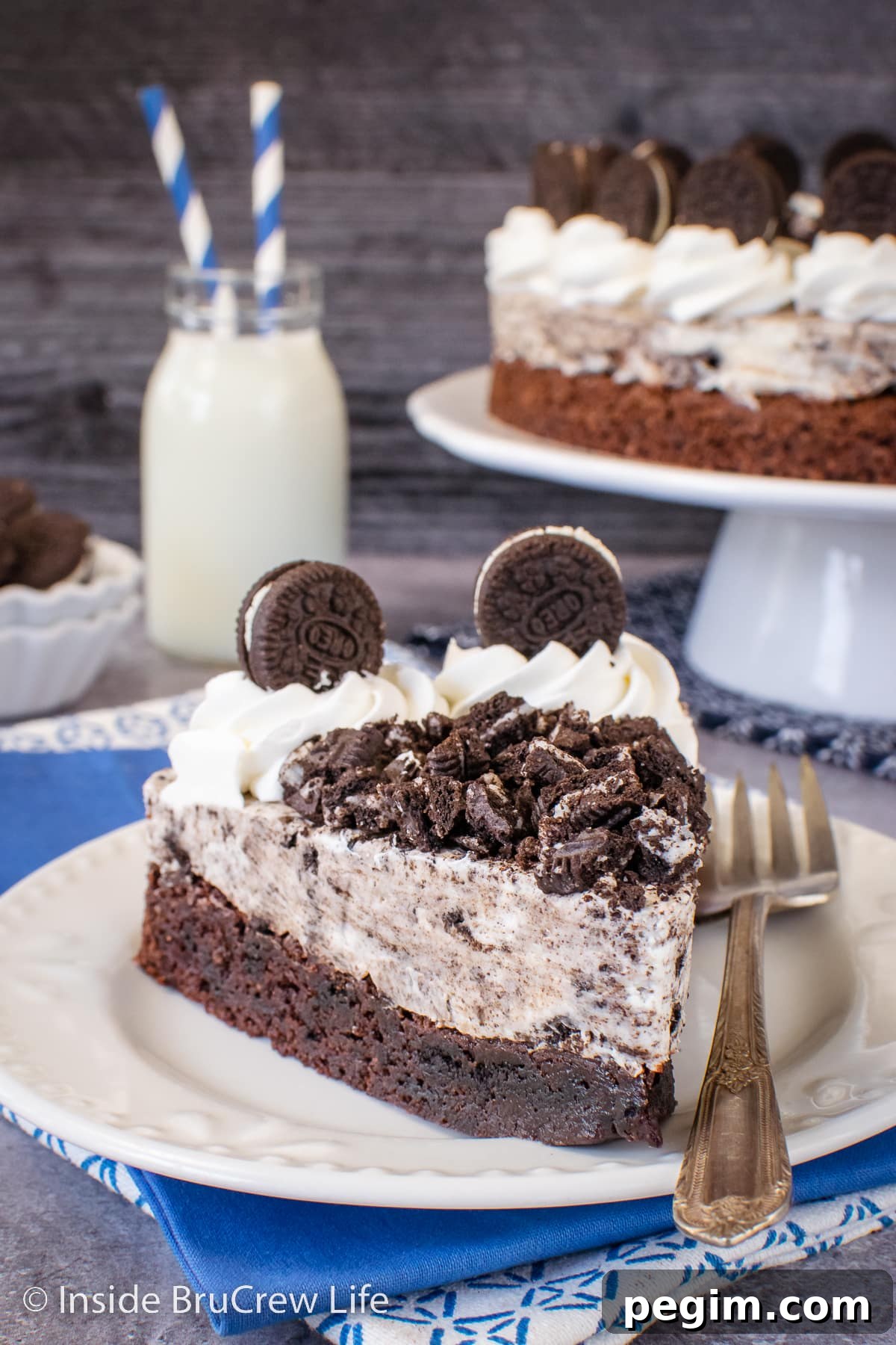 A slice of brownie cake topped with Oreo mousse on a white plate.