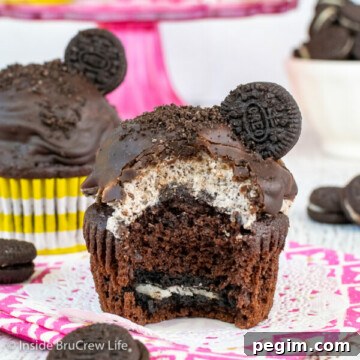 A chocolate cupcake with an Oreo in the bottom and cookies and cream frosting dipped in chocolate