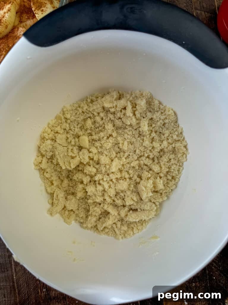 Softened butter cut into flour and sugar mixture in a white mixing bowl.