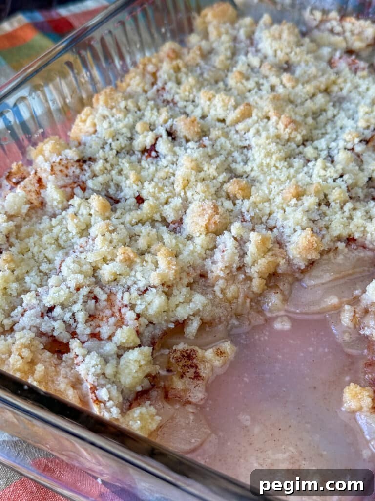 Layers of apples in a simple sauce with golden brown crumbly topping on a large dish of apple crisp.