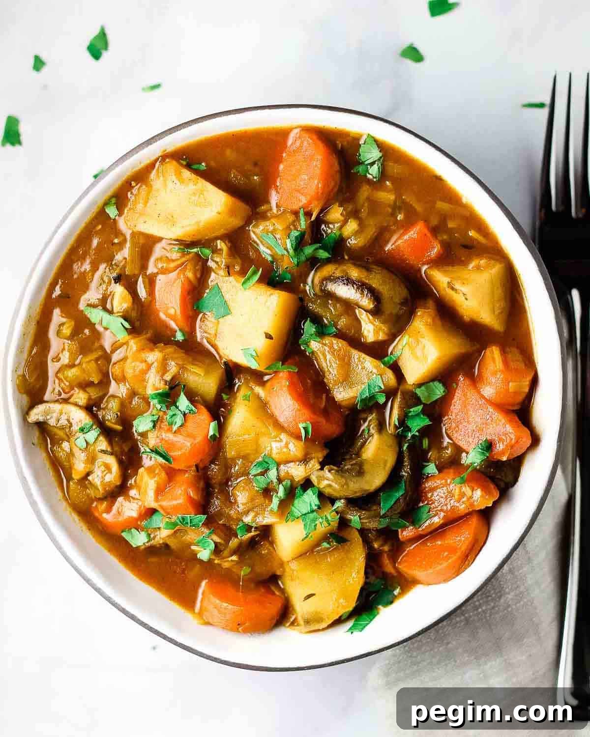 Overhead view of a bowl of vegan stew with a fork beside it.