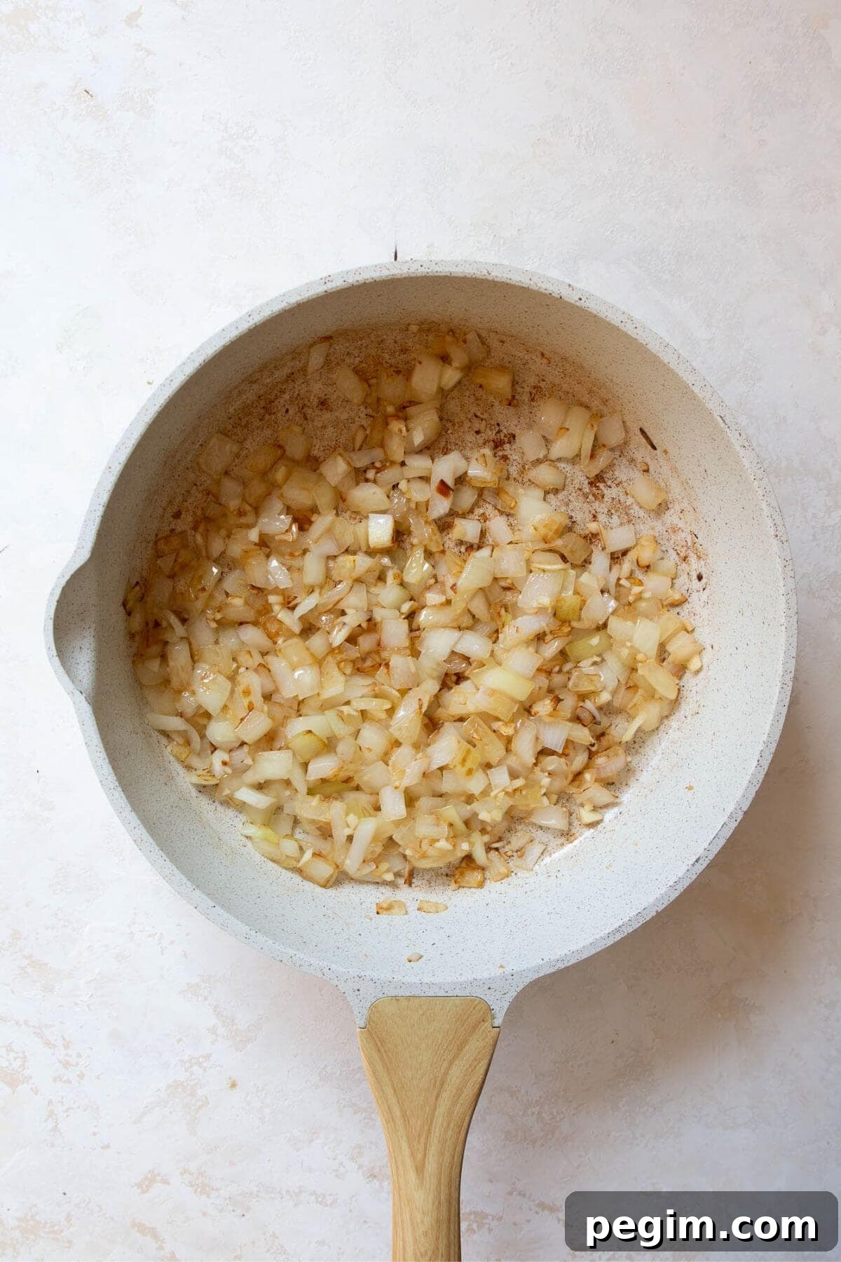 Onions and garlic sautéing in a skillet with olive oil until softened and fragrant.