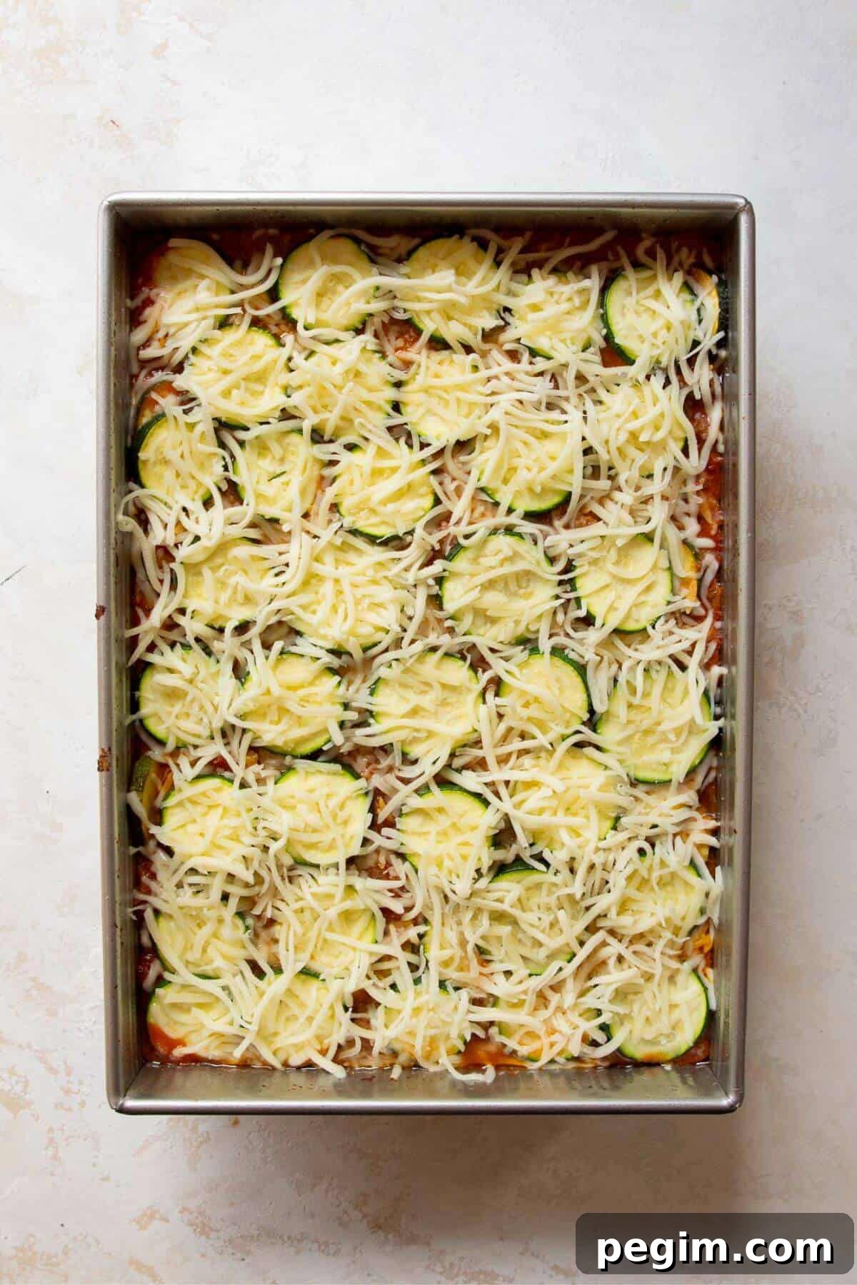 Adding a top layer of zucchini rounds and sprinkling mozzarella cheese over the ground beef casserole before baking.