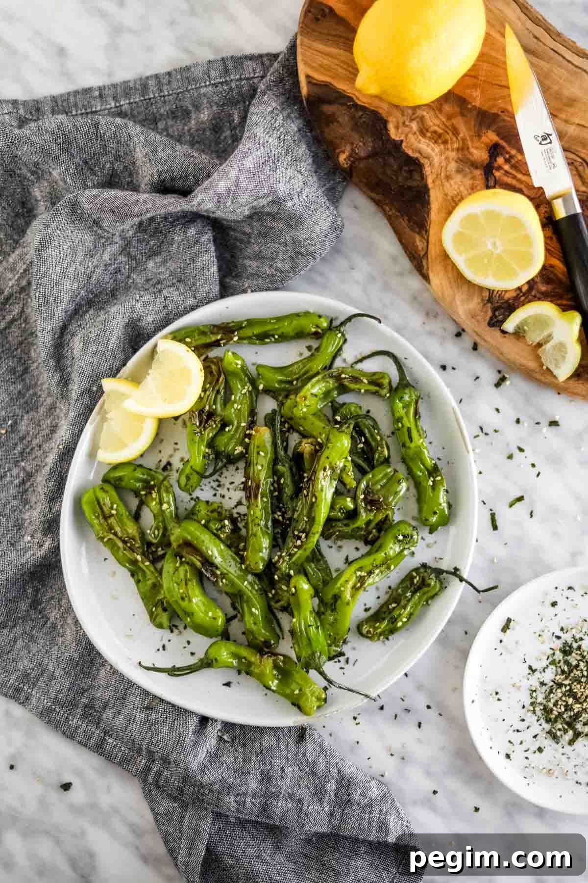 20 Delicious Side Dishes to Serve with Roasted Chicken 19 Shishito Peppers with furikake and lemon on plate flatlay.
