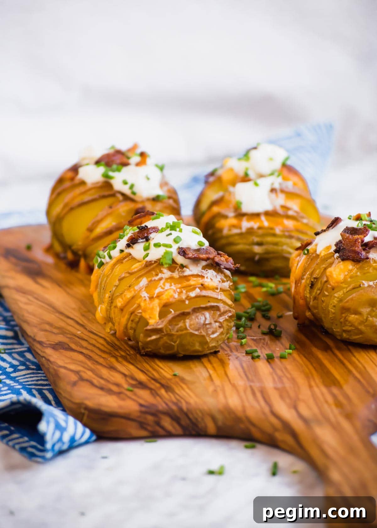 20 Delicious Side Dishes to Serve with Roasted Chicken 9 Bacon Cheddar Hasselback Potatoes on cutting board.