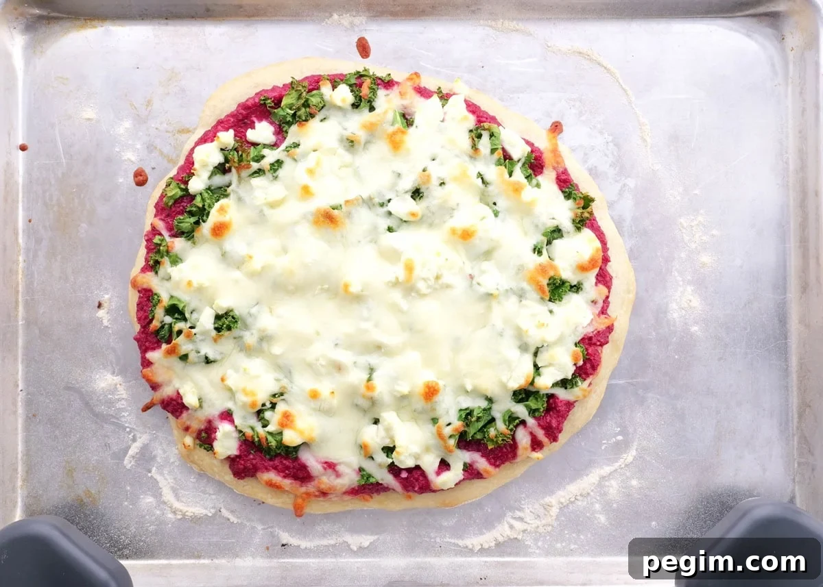 Homemade pizza fresh out of the oven with beet pesto, kale and goat cheese.