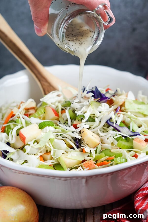 A homemade poppy seed dressing is poured over the apple coleslaw