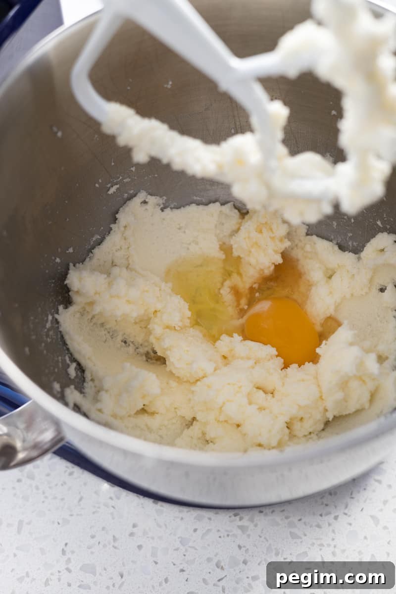 Egg added to the creamed butter mixture in a mixing bowl.