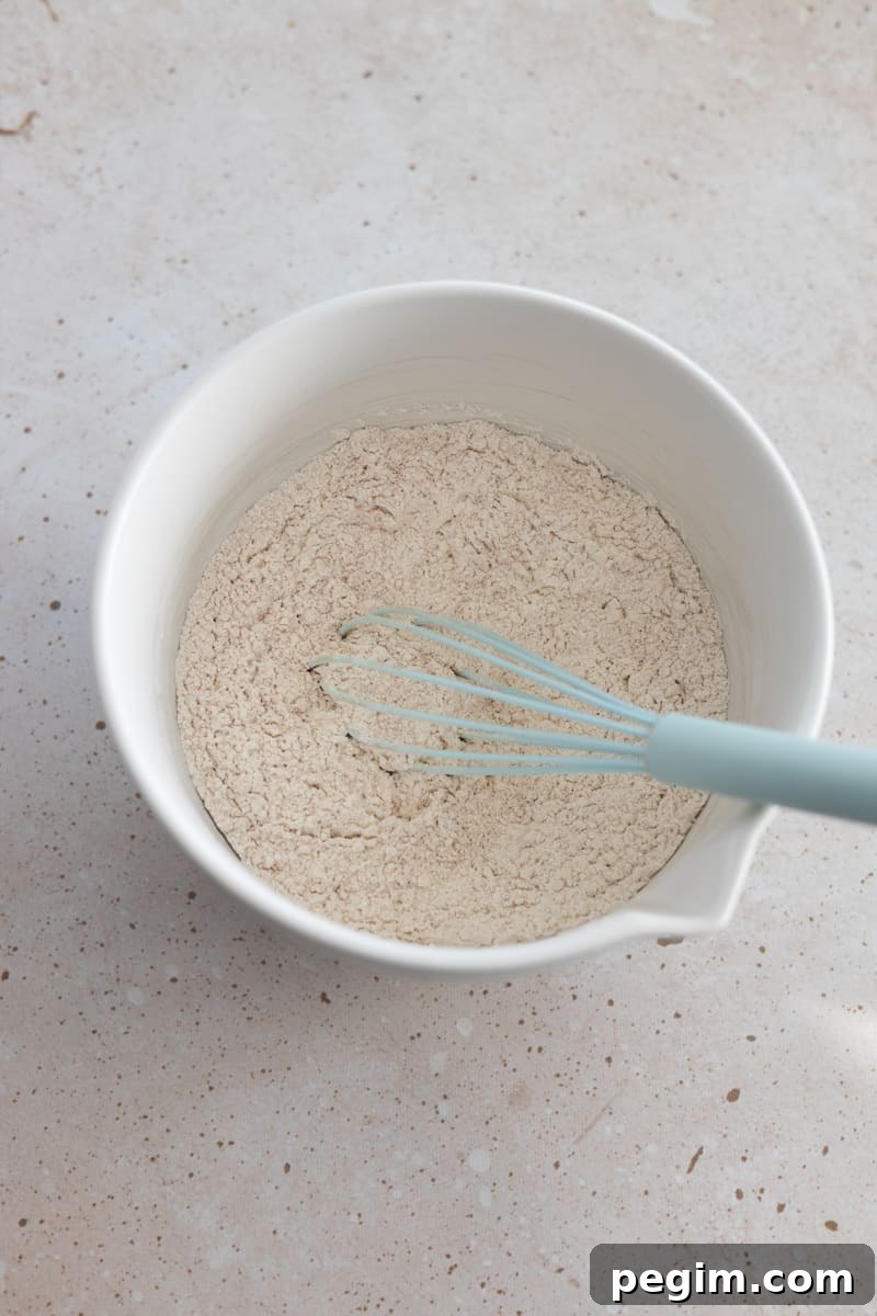 Dry ingredients in a white bowl with a whisk.
