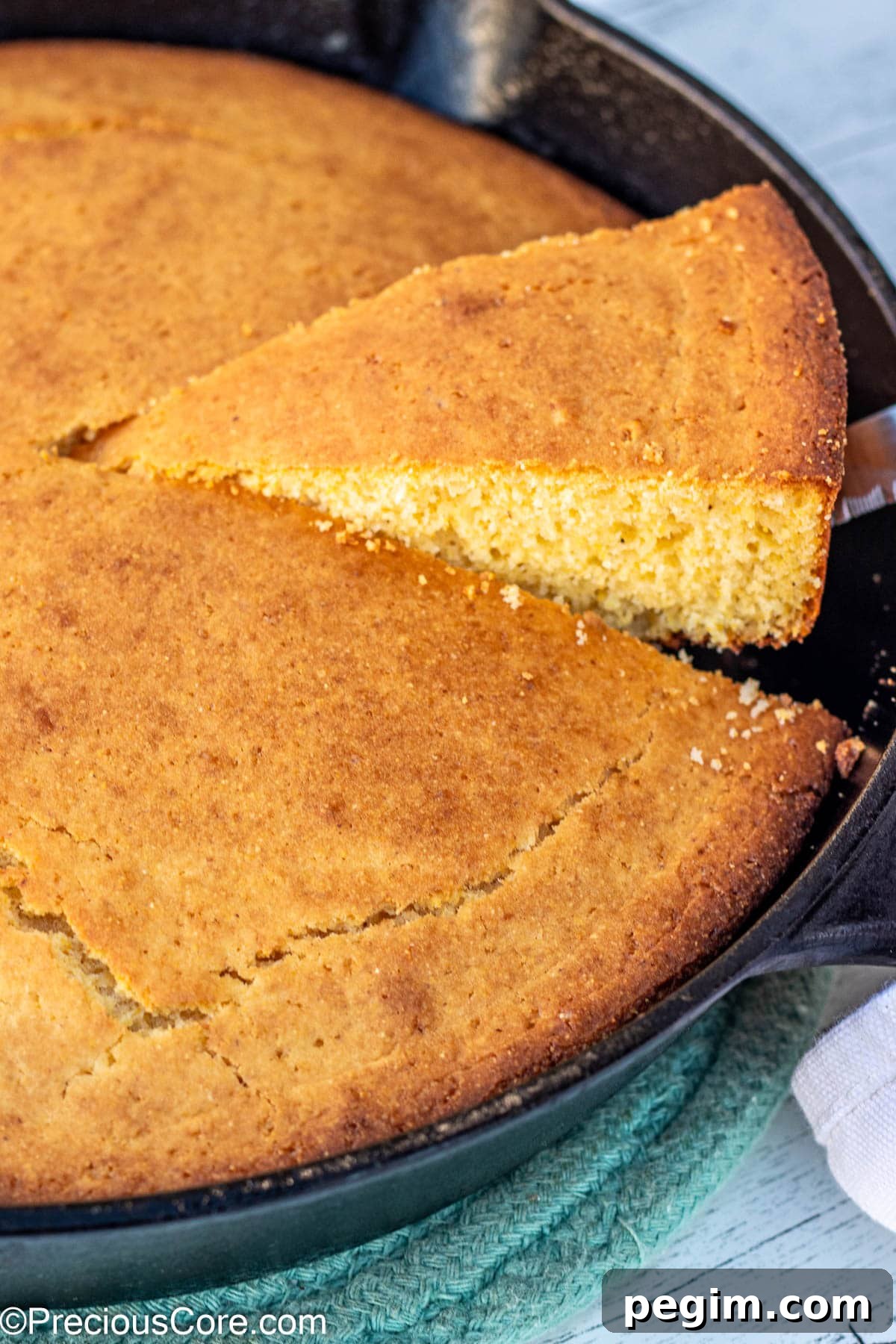 Slice of cornbread being lifted from a cast iron skillet.