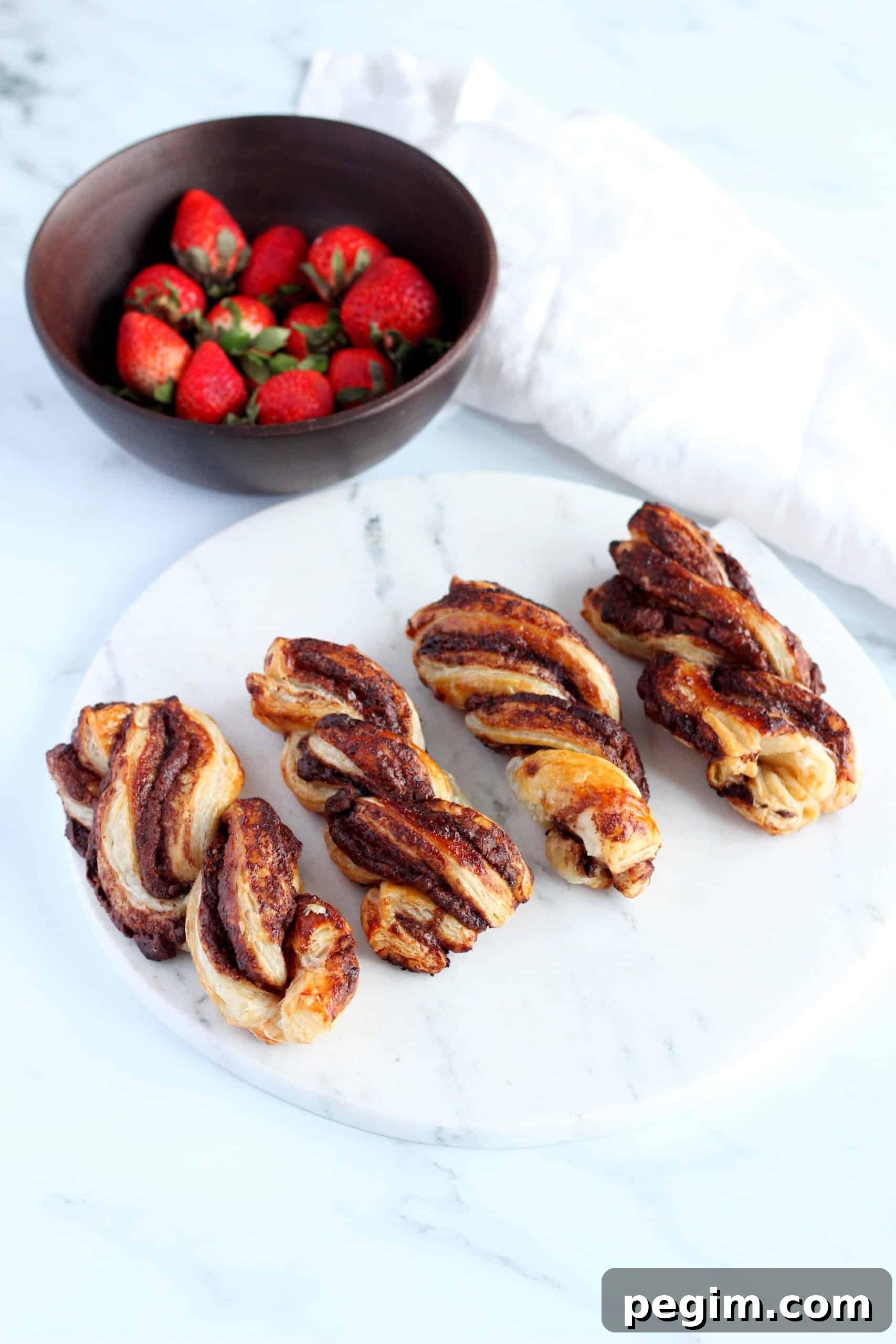 Nutella's twist on marble plate with strawberries in a wooden bowl.