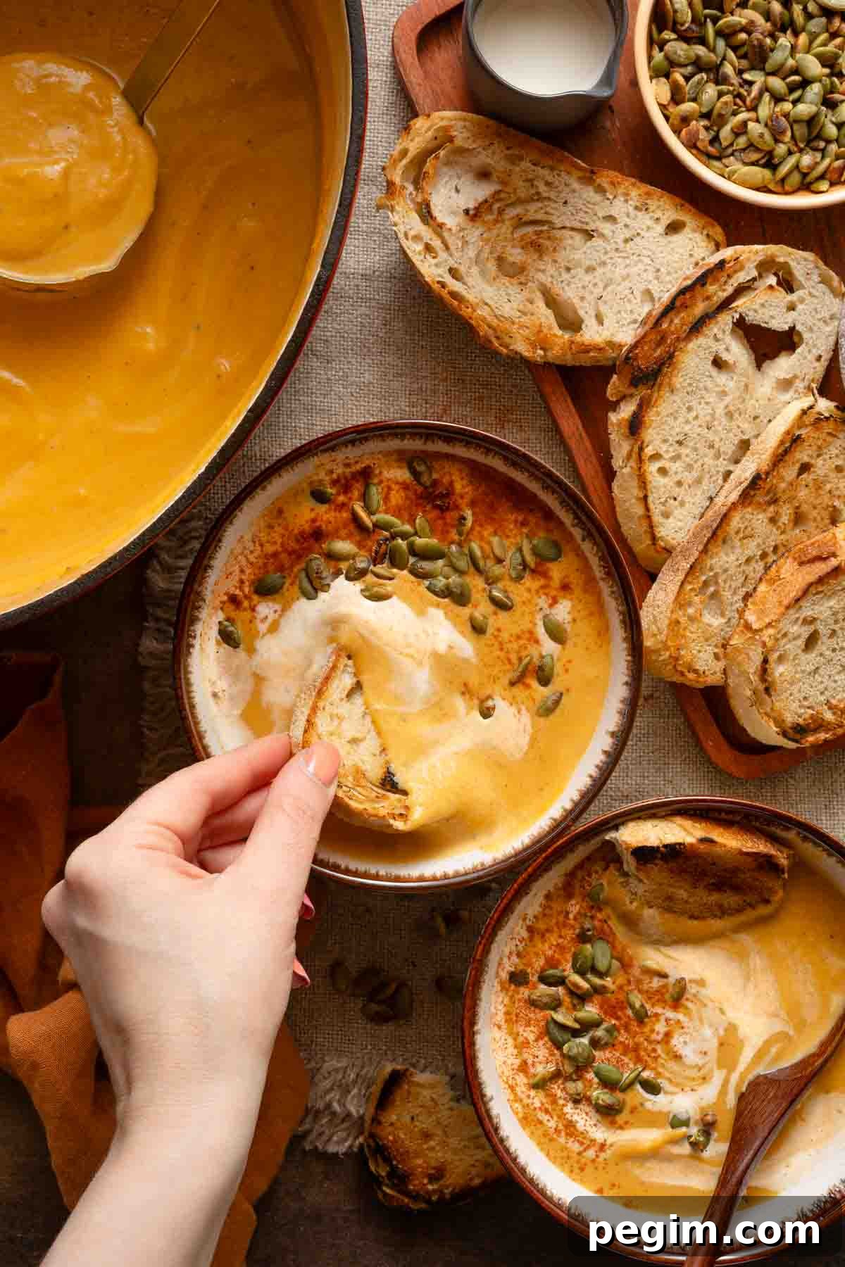 bread being dipped into bowls of sweet potato pumpkin soup.