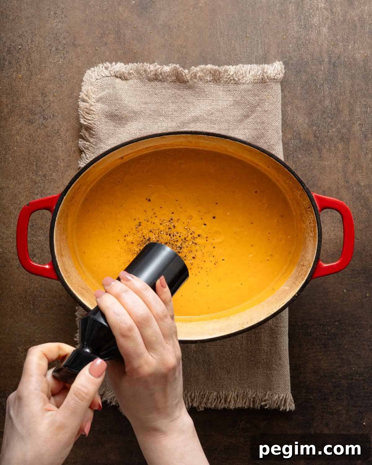 pepper being added to sweet potato soup.
