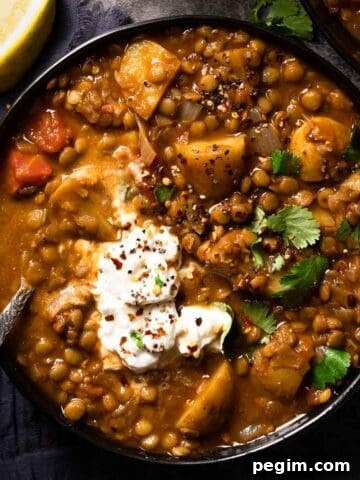 lentil potato soup in bowl with spoon in bowl and lemon wedge on the side